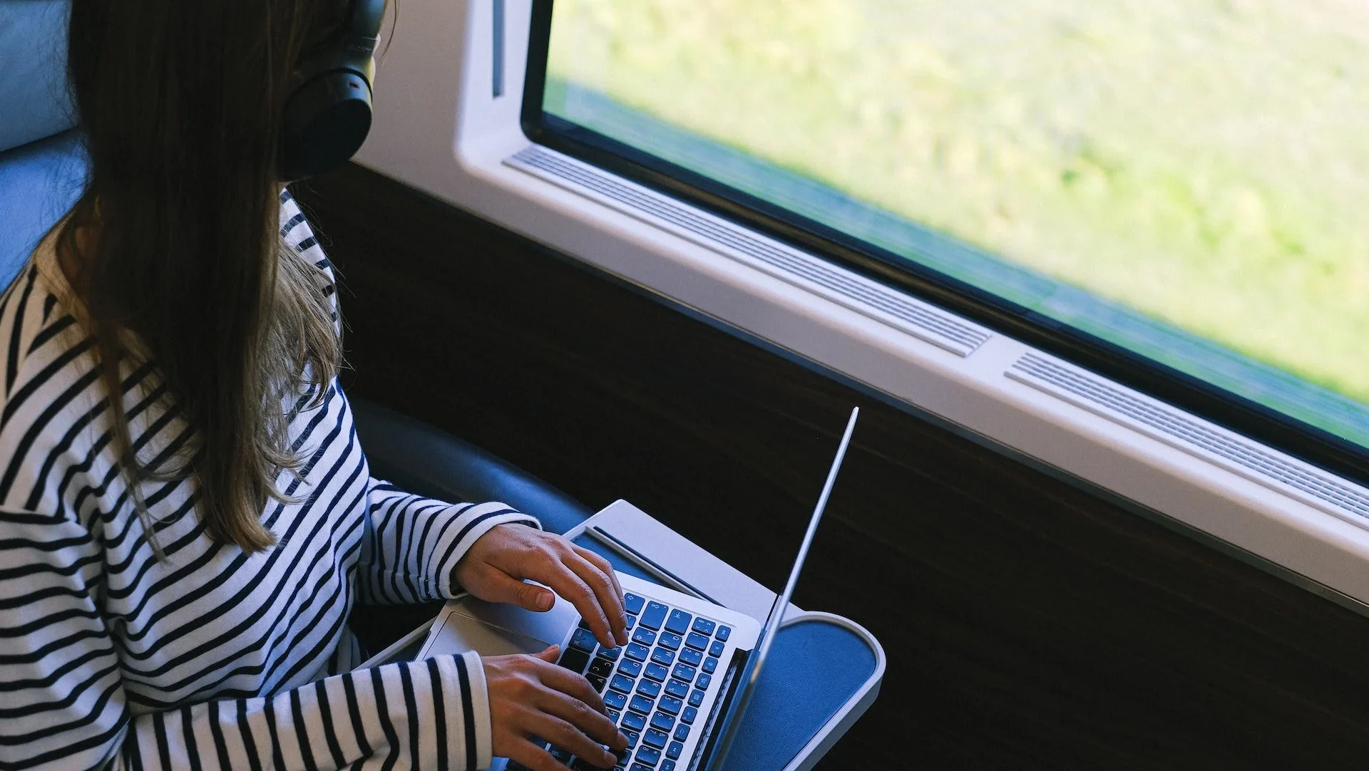 Woman sat on train at laptop and looking out of the window Woman sat on train at laptop and looking out of the window