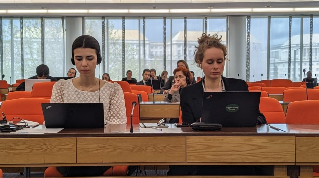 Two women sat side by side at laptops in plenary room