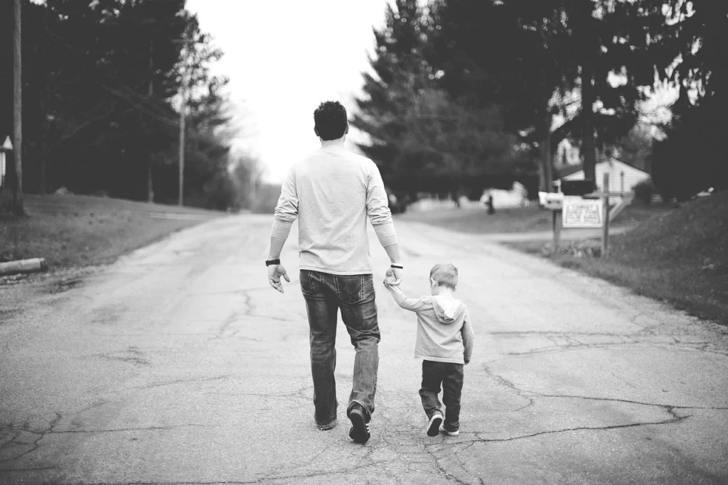 Dad and child holding hands and walking down the street