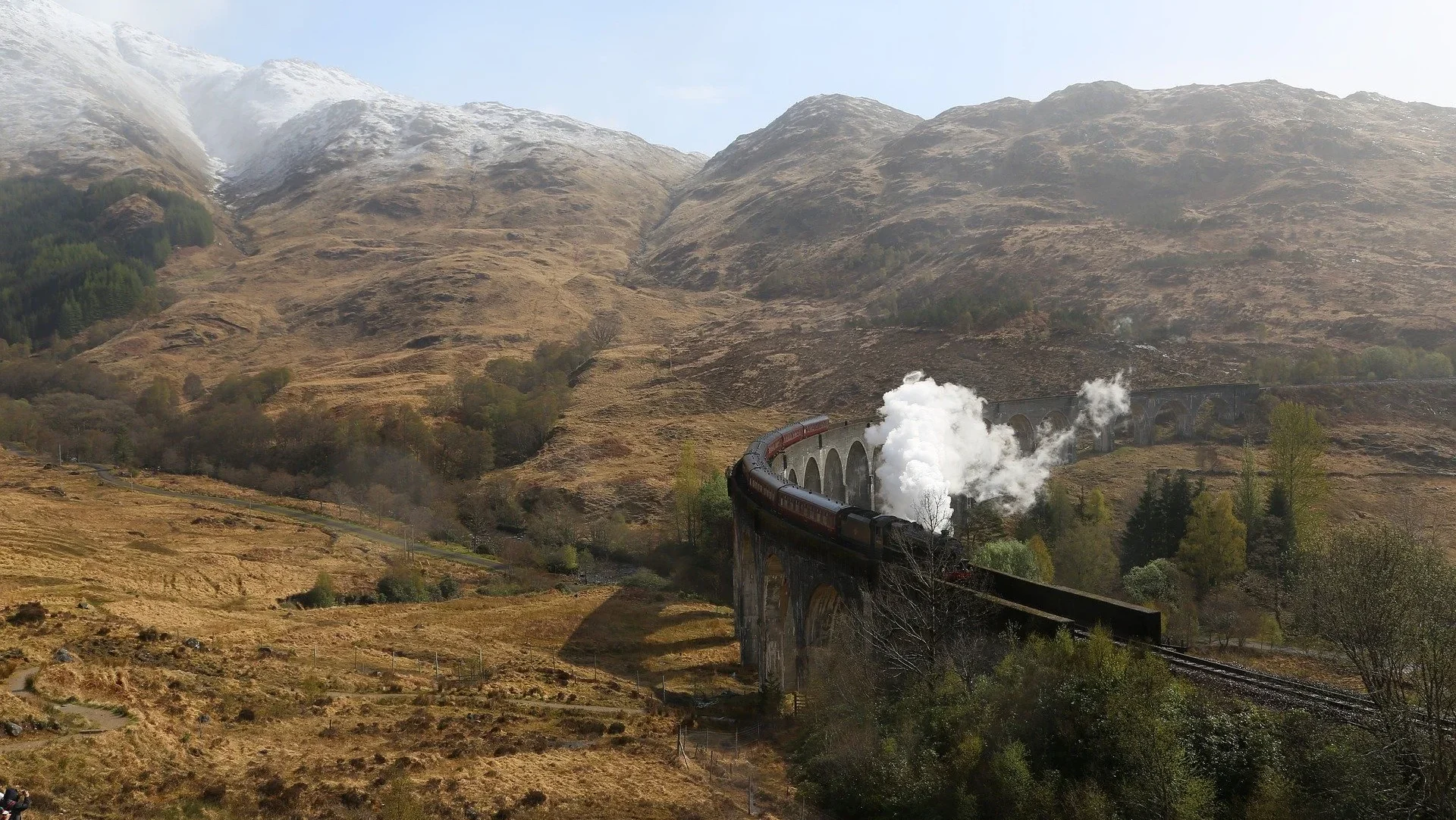 Steam train travelling across viaduct surrounded by mountains Steam train travelling across viaduct surrounded by mountains