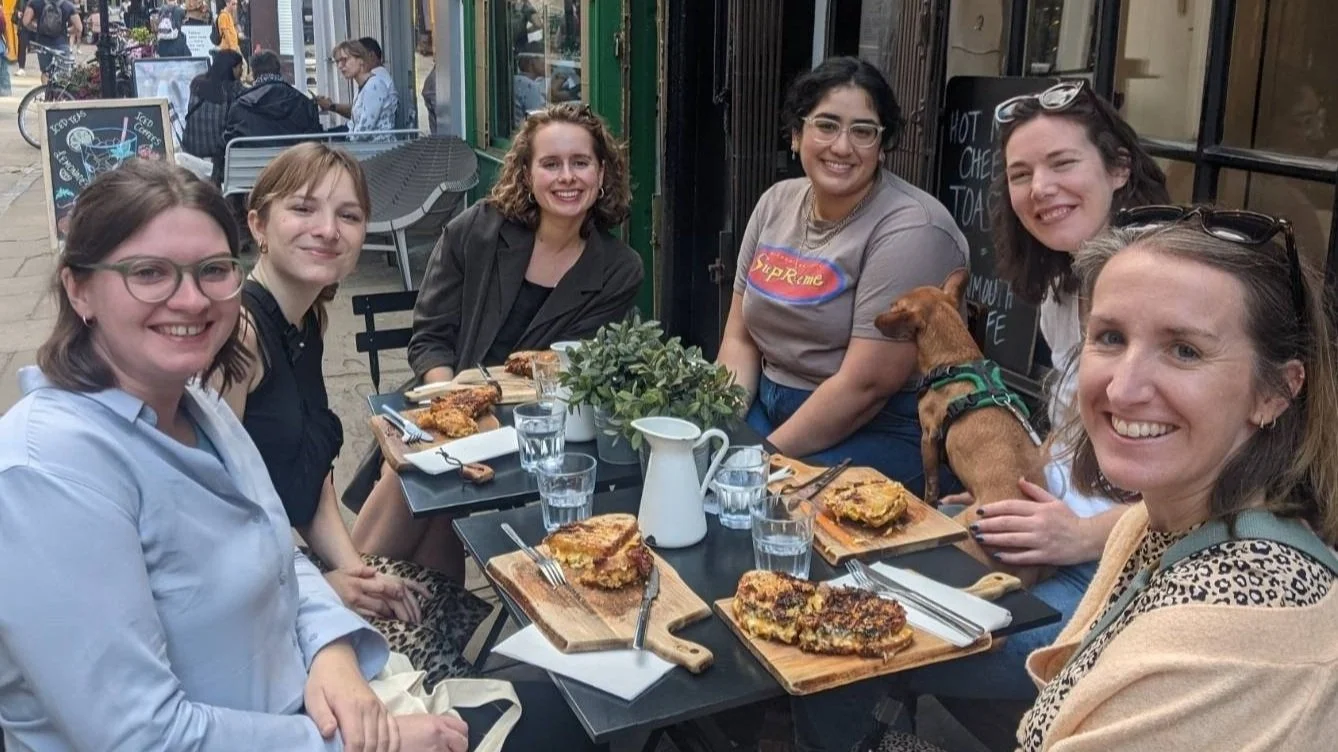 Group of women sat around restaurant table eating Group of women sat around restaurant table eating