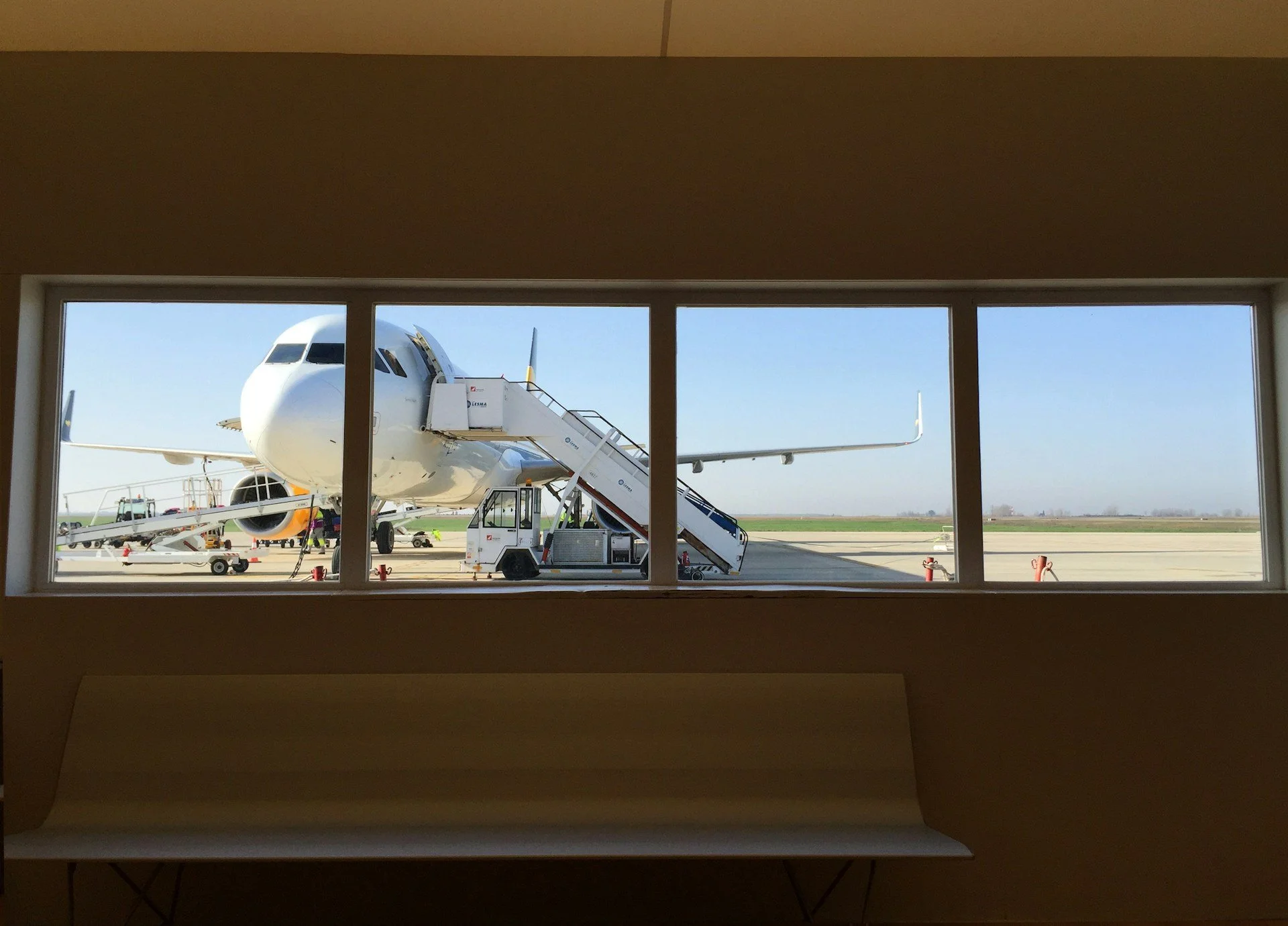 A view of a plane on the tarmac through an airport window A view of a plane on the tarmac through an airport window