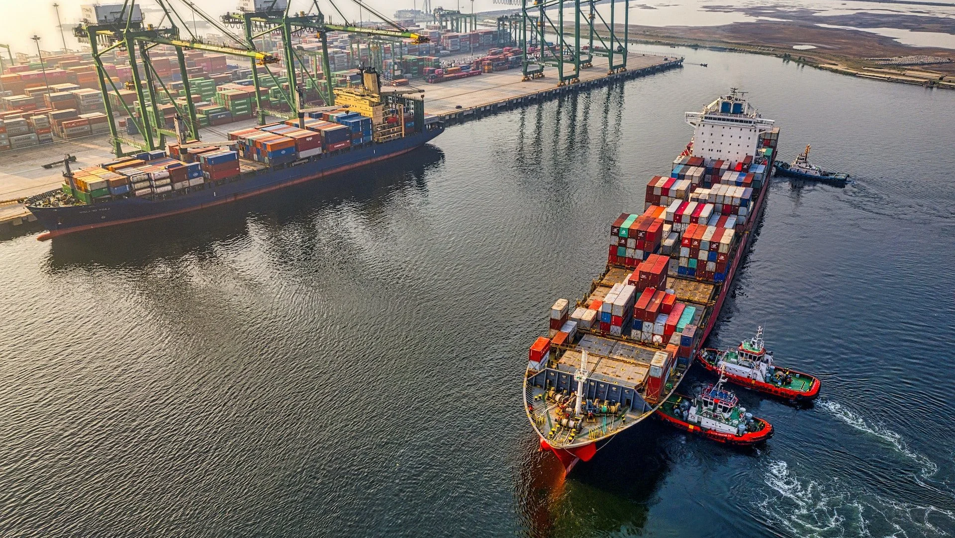 A colourful ship carrying freight close to a dock
