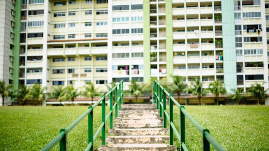Steps and green railings leading to a block of pale green-coloured apartments