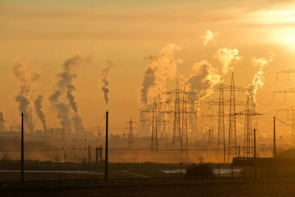 Industrial chimneys belching out thick white smoke into the sky at sunrise