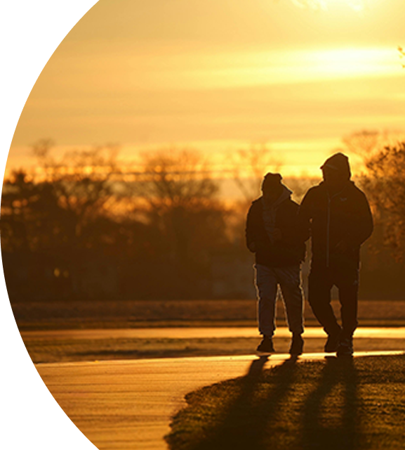 Two people walking arm in arm at sunset