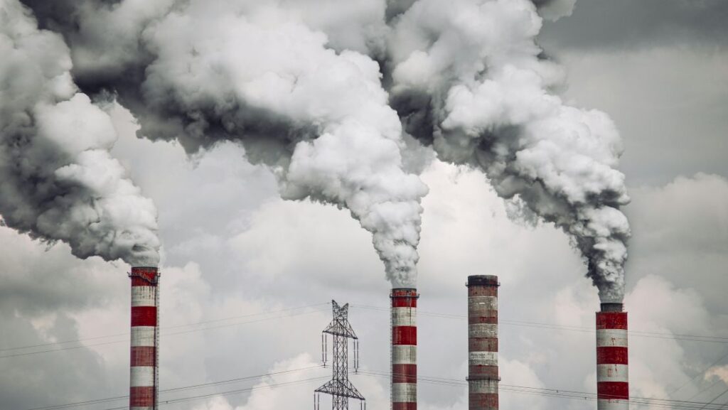 Red and white striped chimneys releasing thick white smoke into the air