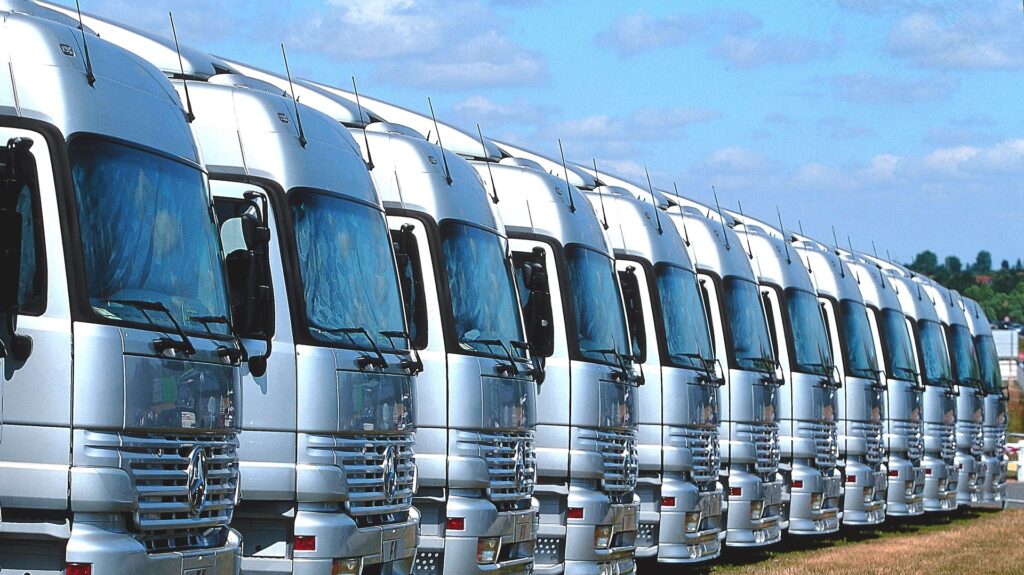 A long line of parked silver-coloured heavy-duty trucks