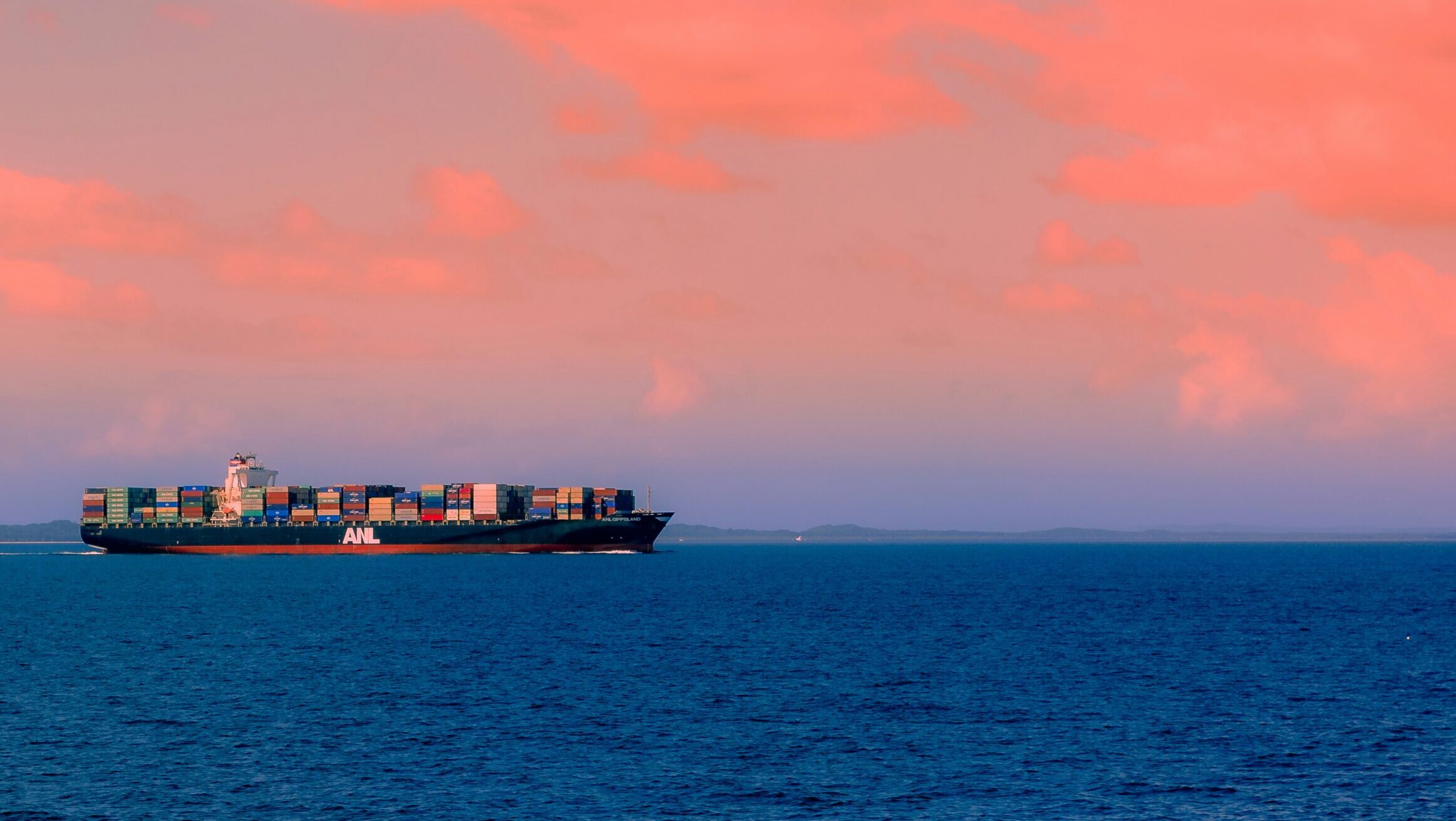 Cargo ship moving through the sea at dusk